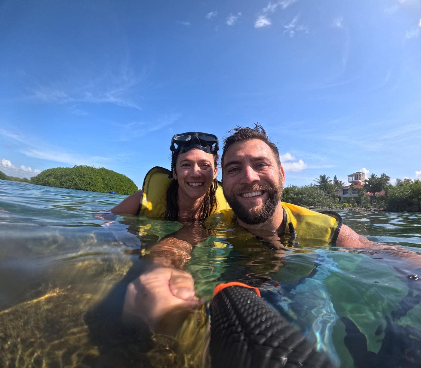 Pareja con chalecos salvavidas dentro del agua de la caleta